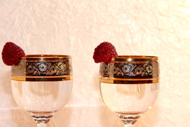 Shots of vodka and raspberries on a white textured background.