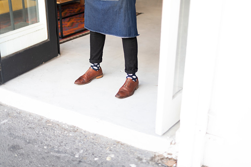 Waiters feet in trendy shoes and socks at entrance to cafe