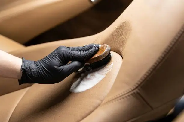Cleaning leather car seat and upholstery with brush. Car detailing