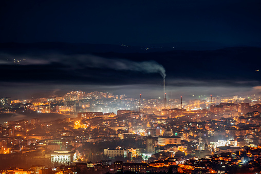 Emission to atmosphere from industrial pipes in the city at night. Smog and air pollution