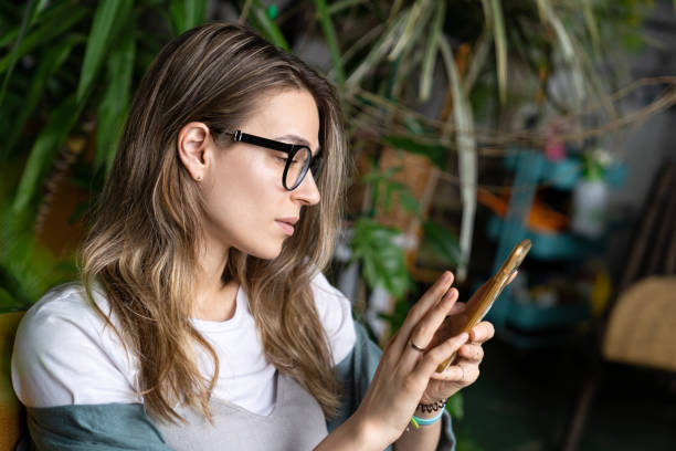 istock woman freelancer in green house, resting, using smartphone and sending message surrounded by exotic plants 1294136829