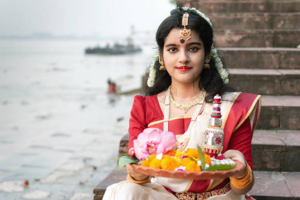 portrait of beautiful indian girl in front of ganga river wearing traditional indian saree, gold jewellery and bangles holding plate of religious offering. - rio carnival fotos imagens e fotografias de stock