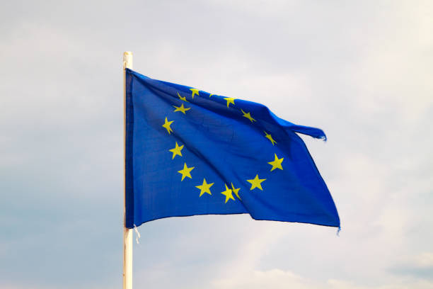 istock European Union flag on a blue sky with clouds background 1294140152