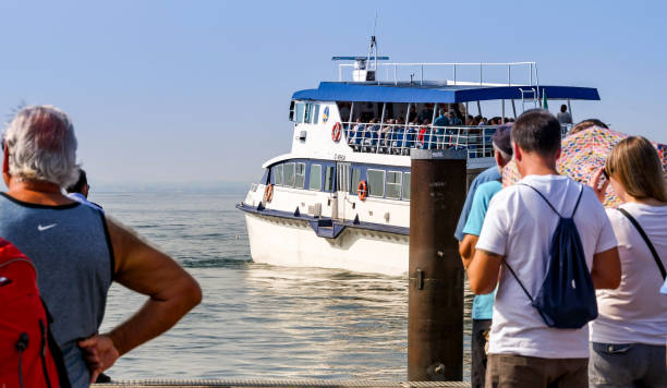 Garda, Lake Garda, Italy - September 2018: People waiting on the jetty as a passenger ferry departs the town of Garda on Lake Garda.