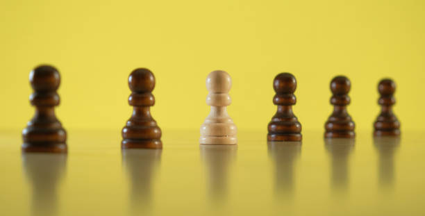 istock Being different and thinking outside the box concept. White pawn among black pawns, selective focus. 1294146576