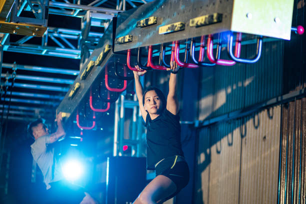 Asian Chinese partner athlete training in an obstacle course. Incline Monkey Bar, Cliff Hanger Asian Chinese partner athlete training in an obstacle course. Incline Monkey Bar, Cliff Hanger obstacle course stock pictures, royalty-free photos & images