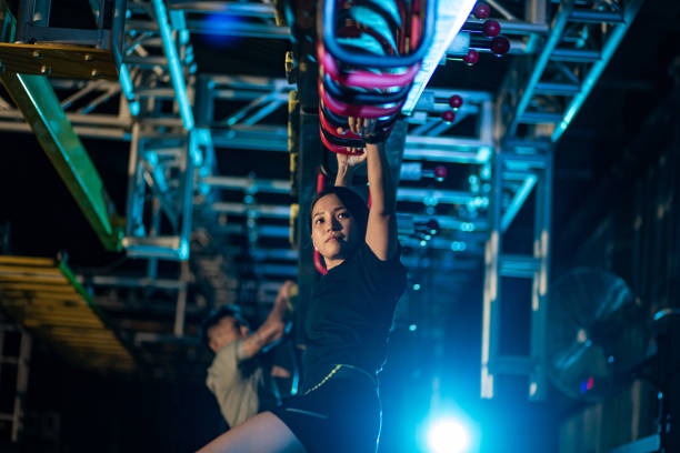 istock Asian Chinese partner athlete training in an obstacle course. Incline Monkey Bar, Cliff Hanger 1294148021