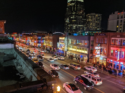 Rooftop photo of Broadway with music bars, venues, and clubs in downtown Nashville on a clear night with a lot of foot and vehicular traffic.
