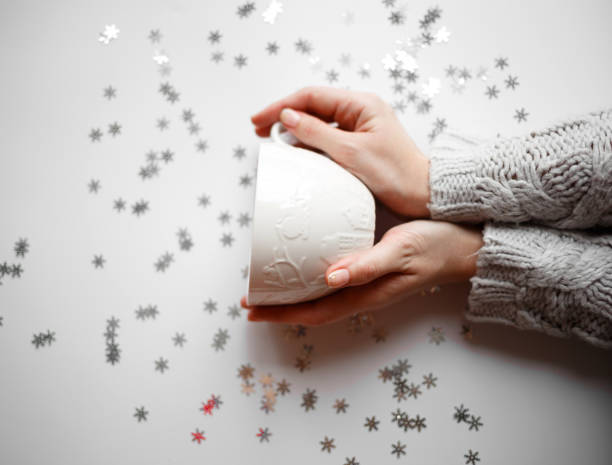 cup with marshmallows on a white background with silver snowflakes