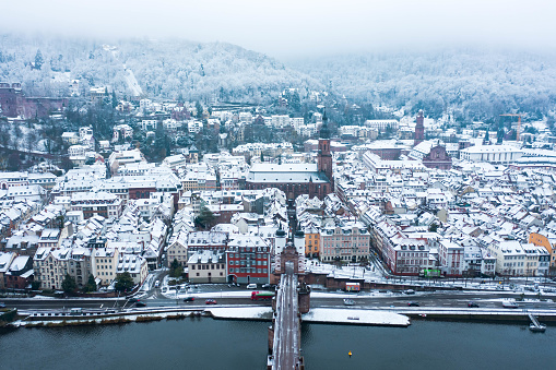 Heidelberg altstadt from above the old bridge after an early winter snow storm. The houses and church in the city center are all covered in fresh snow.