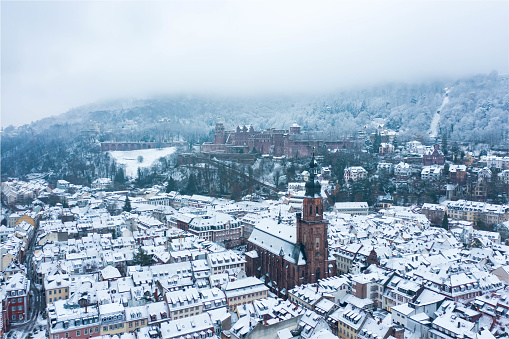 The historic old town of Heidelberg in southern Germany after an early winter snow storm. The image shows the holy ghost church and the famous Heidelbegr castle in the background.