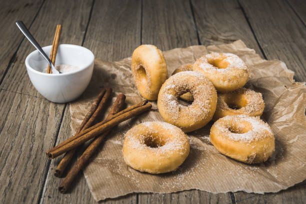 istock Mini donuts with sugar and cinnamon on a paper on a wooden table 1294159134