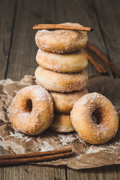 Sugared stacked mini donuts with cinnamon on a wooden table, vertical