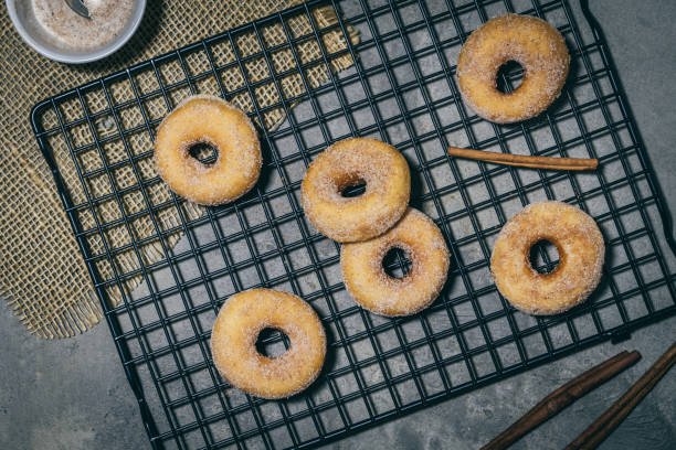 istock Sugared mini donuts with cinnamon on a cooling rack on a gray background, top view 1294159273
