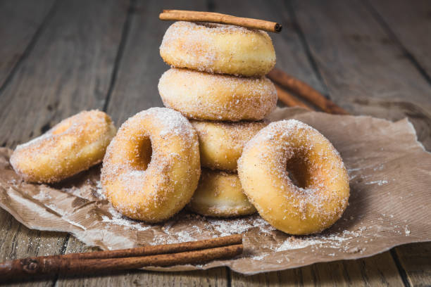 istock Sugared stacked mini donuts with cinnamon on brown paper on a wooden table 1294159316