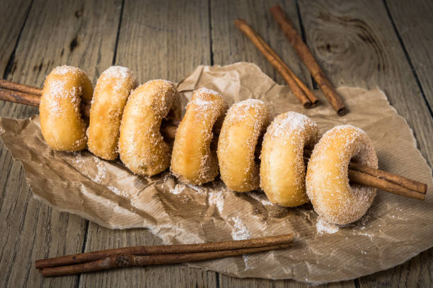 istock Sugared mini donuts lined up on a cinnamon stick on a wooden table 1294159350
