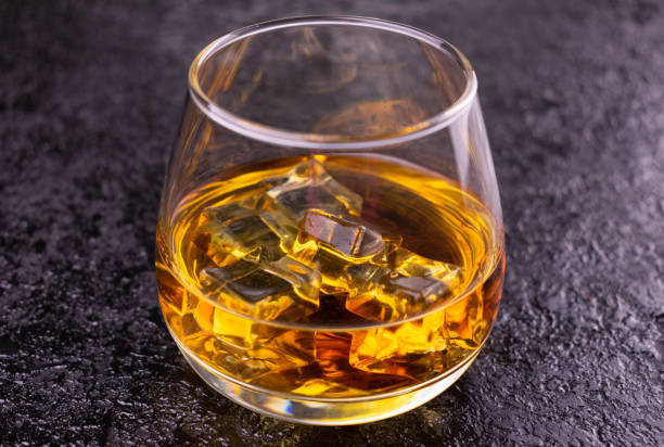 istock Glass of cognac with ice on a black background. 1294165683