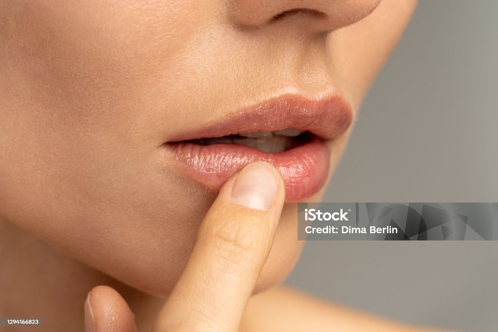 Close up of woman applying moisturizing nourishing balm to her lips with her finger to prevent dryness and chapping in the cold season Close up of woman applying moisturizing nourishing balm to her lips with her finger to prevent dryness and chapping in the cold season. Lip protection. Human Lips Stock Photo