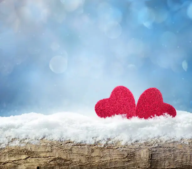 Winter snow bright background. Holiday landscape with wood, snowdrifts and red hearts in the snow. Valentines Day.