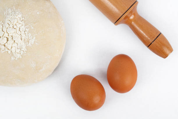 Dough with flour, olive oil, eggs and rolling pin.