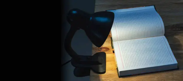 A desk lamp illuminating a notebook in pitch darkness