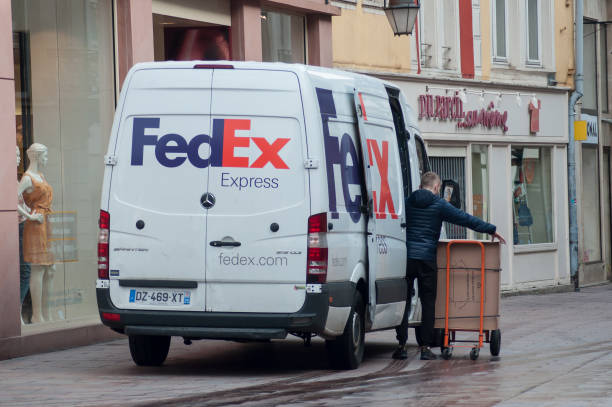 delivery man unloading goods from Fedex delivery truck parked in the street near fashion store Mulhouse - France - 17 May 2018 - delivery man unloading goods from Fedex delivery truck parked in the street near fashion store mulhouse photos stock pictures, royalty-free photos & images