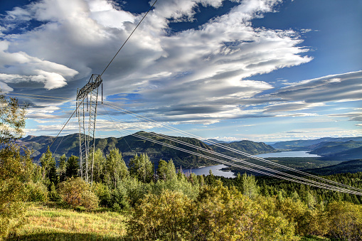 Scotch Creek, BC - July 19, 2014: High tension electricity power transmission lines high above Shuswap lake in the interior of British Columbia
