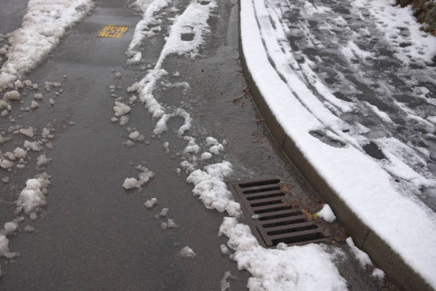 9 - Road and pavement covered in thawing snow. Road is partially cleared by cars, but sledge tracks and footsteps still line the pavement.