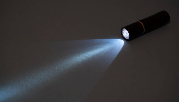 istock Closeup pocket LED flashlight in the dark. Small bicycle torch. Light ray of LED torch. Flashlight for camping 1294183154