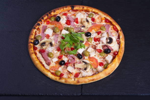 istock A beautiful pizza with tomatoes, meat and cheese lies on a dark stone table 1294184271