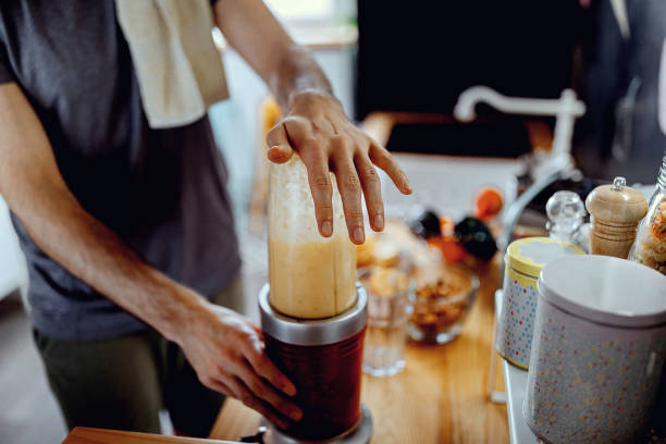 istock Young man is making a smoothie after exercising at home 1294185098