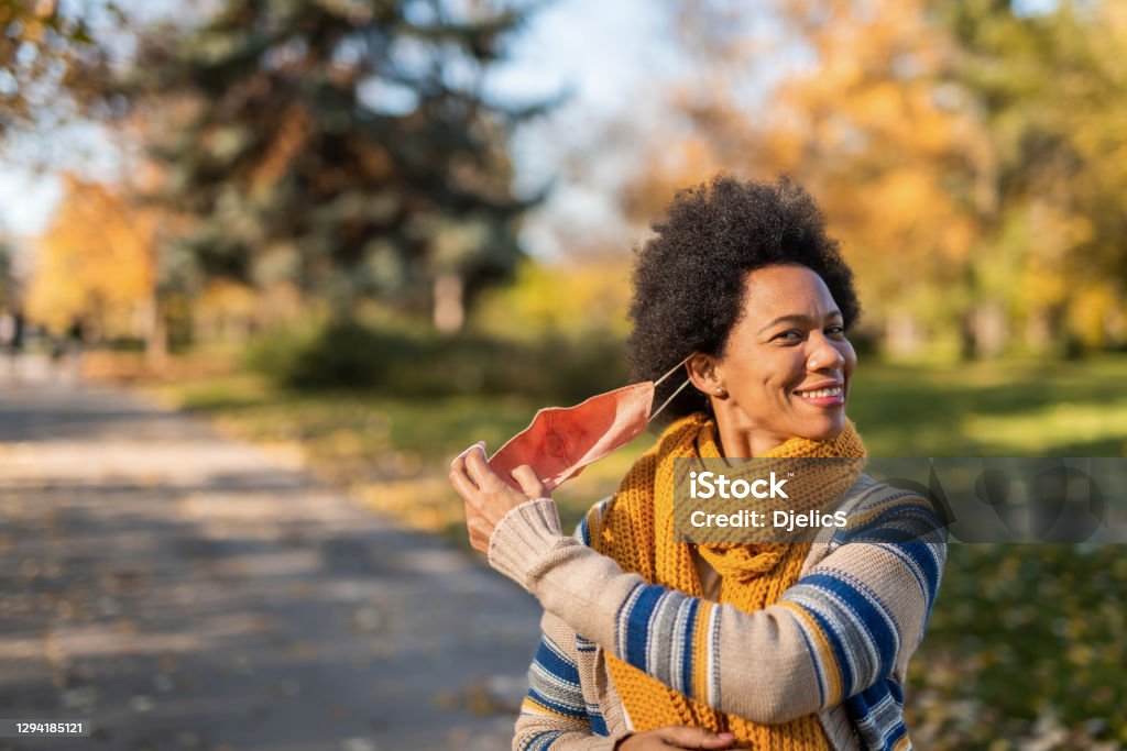 African American woman taking off face mask. Happy African American woman setting her self free from the face mask. Hope for end of pandemic concept. Protective Face Mask Stock Photo
