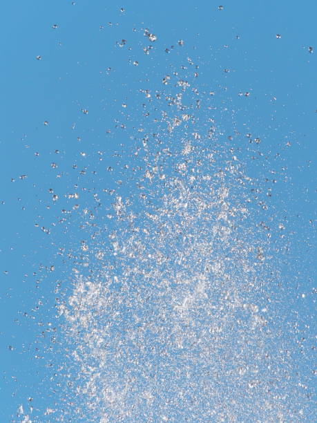 Tops of large fountain jets gushing upwards against blue sky, may be used as background