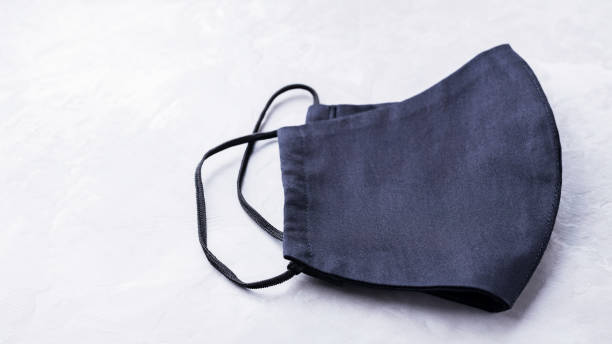 istock Face protective mask on ultimate gray background. Antivirus mask made from black cotton. Black face homemade mask to protect against flu and virus. Copy space. Top view 1294195233