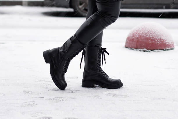 istock Female legs in black winter shoes 1294200599