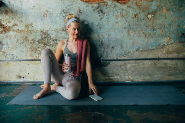 istock Fitness at Home: Happy Blonde Woman Using a Mobile Phone App to Exercise 1294200775
