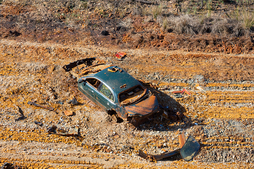 Riotinto red landscape,a crashed car in the reservoir wall, a sunny day, all the car broken by accident and vandalism...