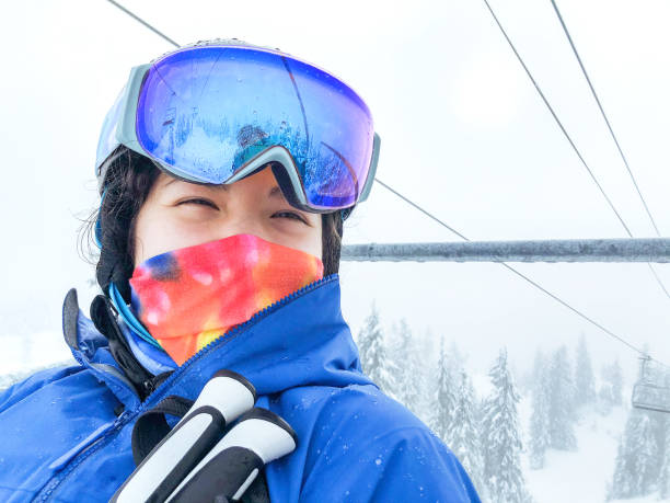 multi-ethnic mujer esquiadora que lleva gaiter de cuello y casco, montar en telesilla - mt seymour provincial park fotografías e imágenes de stock