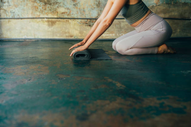 istock Yoga at Home: Hands of an Anonymous Woman Unrolling her Exercise Mat on the Floor 1294207566
