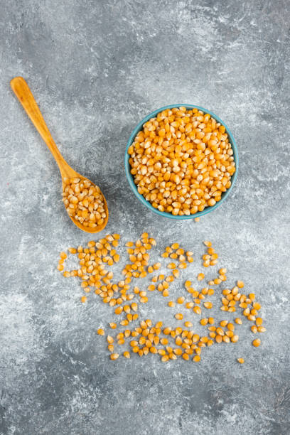 istock Uncooked corn kernels in blue bowl with wooden spoon 1294213913
