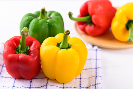 Fresh yellow, red and green bell peppers on fabric, Organic vegetables