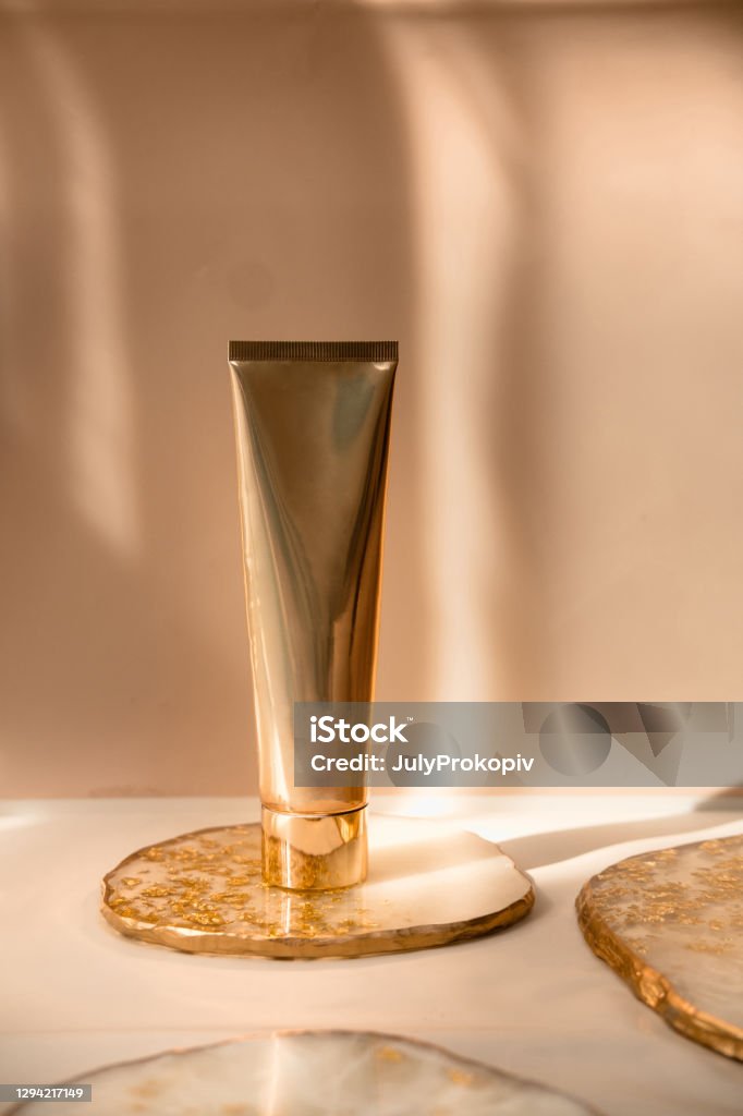 Golden cosmetic tube on pastel color minimalism beauty Golden cosmetic tube light pastel color background, lights and shadows. Natural minimalism. Minimal still life. Beauty blogging, branding layout,  skin care ad mock up, copy space Skin Care Stock Photo