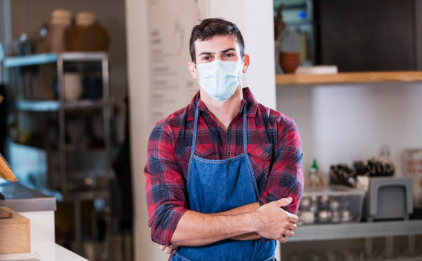 istock Hispanic man working in cafe with mask during covid-19 1294217176