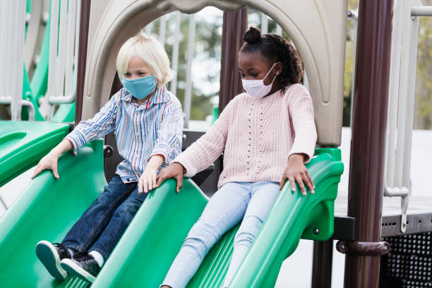 istock Two children on playground slide, wearing face masks 1294218699