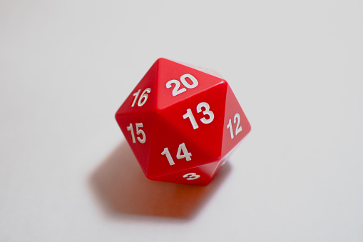 A red twenty sided die, showing 20, also known as a d20. These dice are often used in table top role playing games.