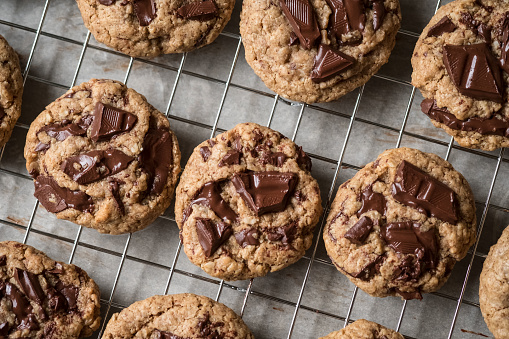 Rows of homemade dark chocolate chip cookies made with healthy vegan ingredients: oat flour, almond flour, almond butter, almond milk, and chopped dark chocolate.  Fresh from the oven with chocolate melting.