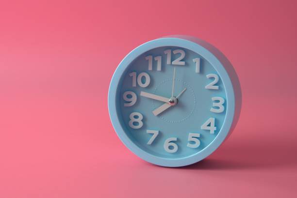 istock Closeup of blue wall clock isolated on pink background 1294239149