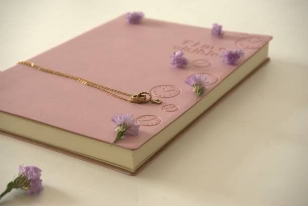 istock Pink diary and metal pendant on table surrounded by flowers 1294239156