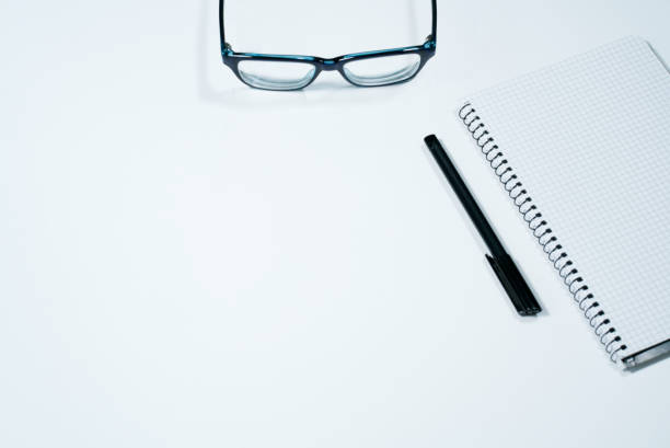 istock Notebook, pen, glasses isolated on white background. Office desk with copy space 1294239229