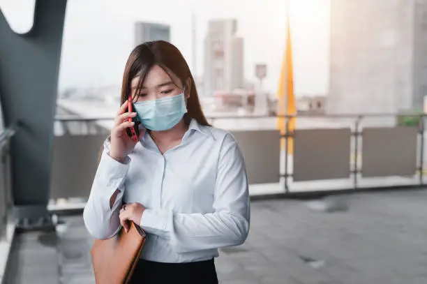 An Asian woman wearing a mask stands in queue waiting for the railcar in the subway. Social Distancing to Prevent Covid 19 Outbreak. Travel concept by railcar. The idea of ​​a businesswomen.